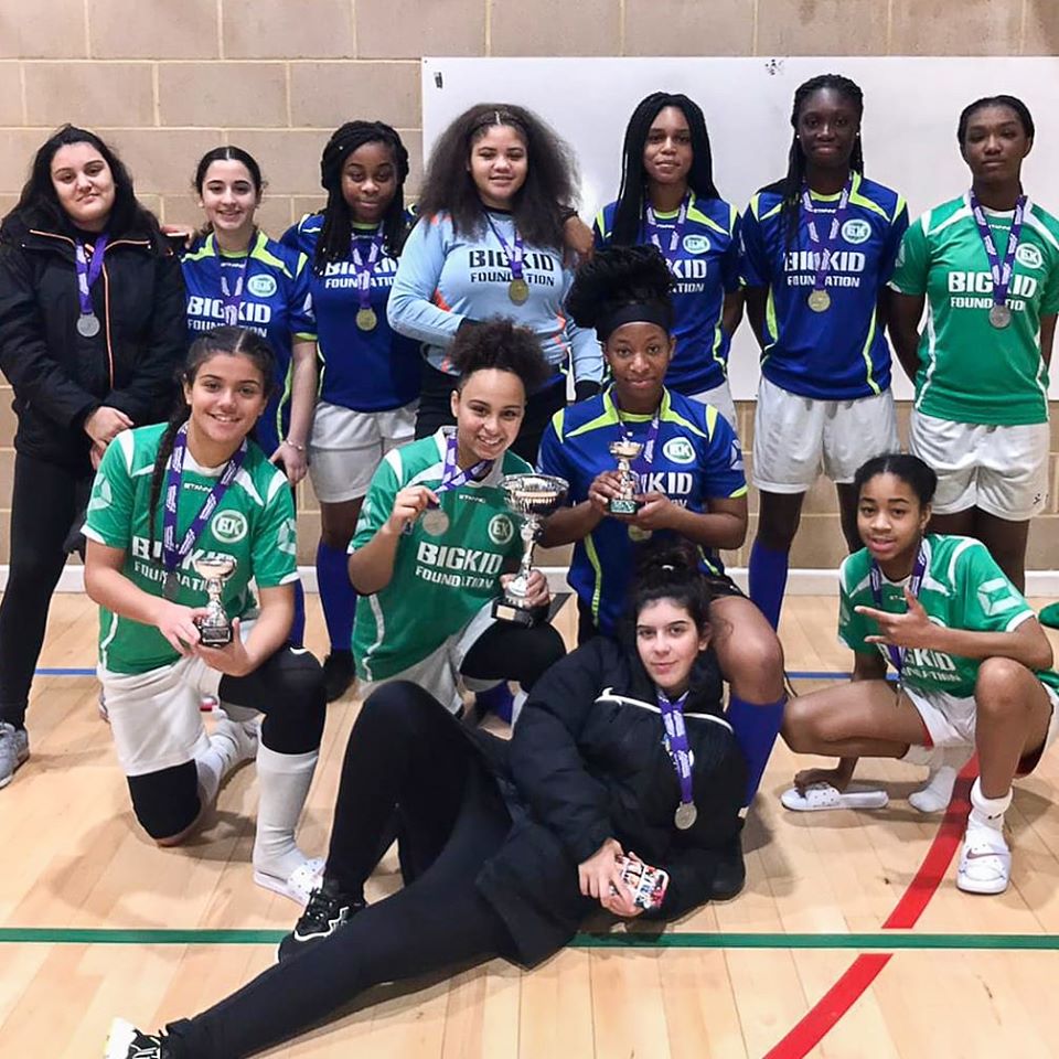 Young female football team holding awards and wearing medals
