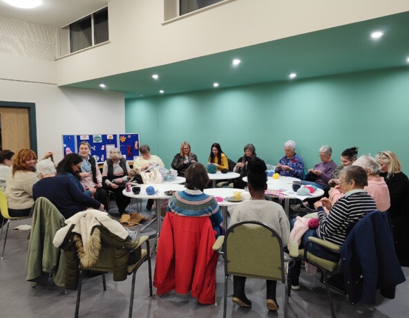 Group of people sitting knitting.
