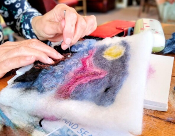 Person needle-felting landscape picture.