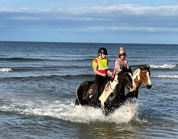Two young riders riding on the foreshore.