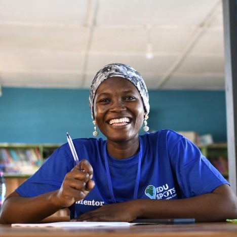 Girl in a blue t-shirt sitting in a classroom holding a pen