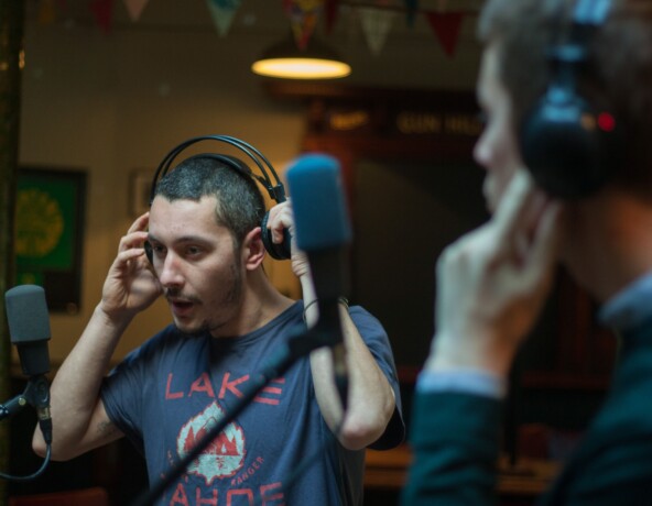 Man wearing headphones standing in front of a microphone