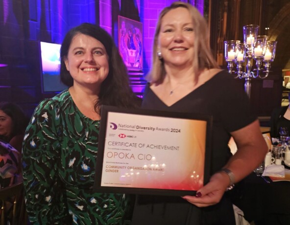 Two women at an awards ceremony holding an achievement award.